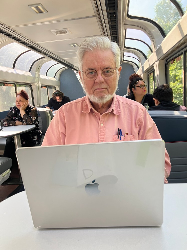 Man typing on laptop in railroad lounge car
